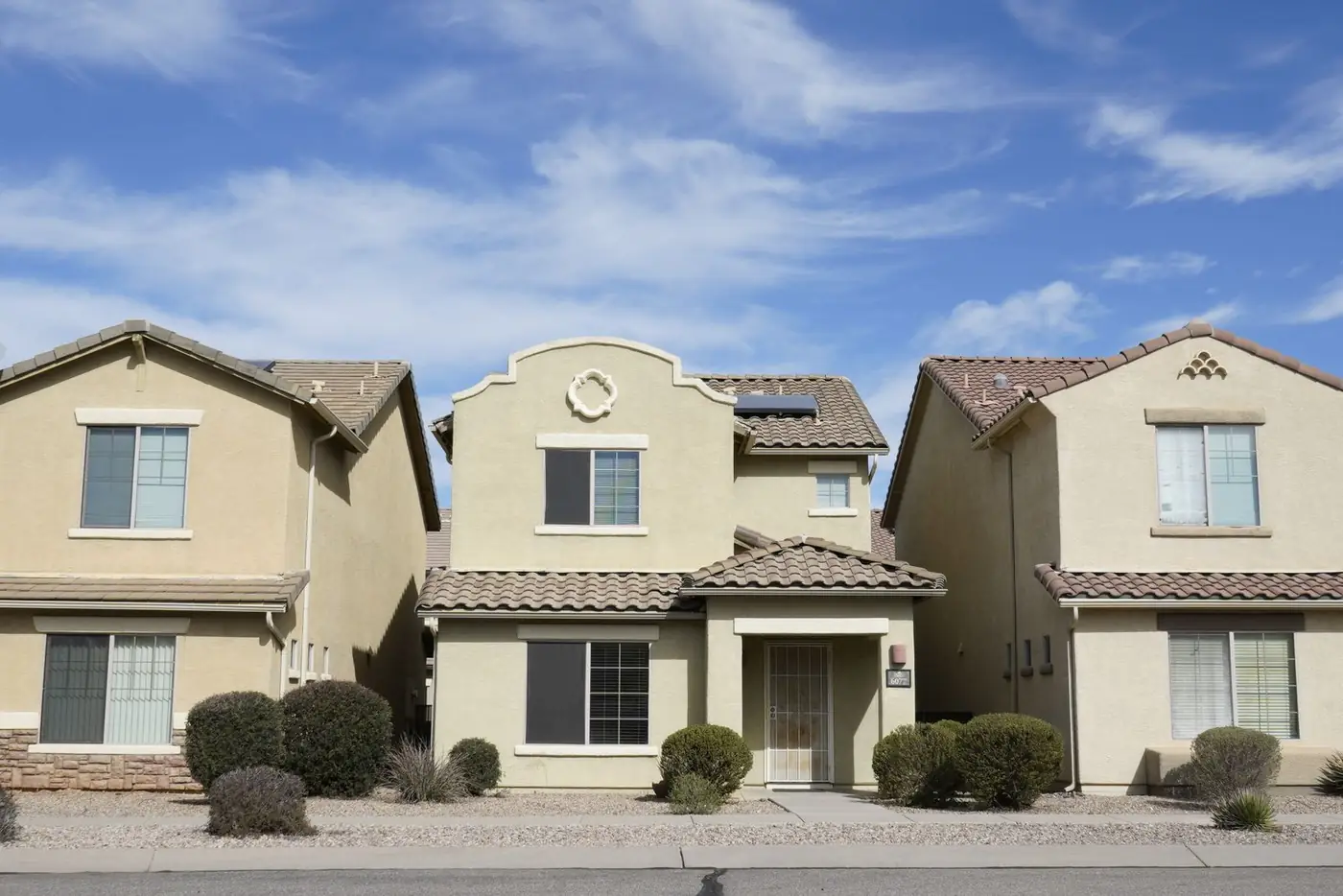 Three adjacent homes in a Tucson neighborhood under a clear sky
