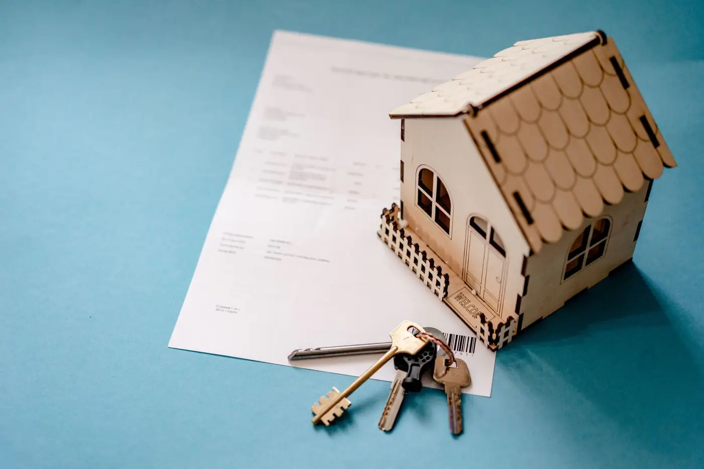 A small wooden house model with keys on a document
